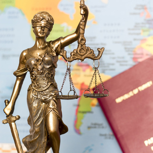 Statue of scales of justice against map and passport backdrop